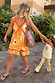 Yellow Sun Mini Dress with orange sun prints and contrast trim, styled on a model with a child for a vacation look.