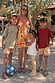 Yellow Sun Mini Dress with a sun print and tie-front, shown with matching kids' outfits in a vacation setting.