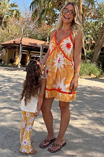 Yellow Sun Mini Dress in cotton with a sun print and orange trims, worn on a beach vacation.
