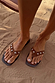 Tan Leather Stud Sandals with silver stud detailing and a square toe, worn on sand for a vacation look.