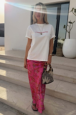 White Rodeo T-Shirt with red lettering and a relaxed fit, styled with a pink patterned skirt and a beaded bag.
