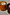 Thumbnail for NFD Eau De Parfum Candle 002 in an orange glass jar, displayed on a textured white surface in bright natural sunlight.