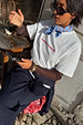 Blue Cotton Stripe Bandana in blue and red, tied at the neck and paired with a graphic tee for a London street style look.