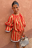 Red and camel Tomato Stripe Blouse with voluminous sleeves and drawstring waist on a model.