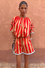Tomato Stripe Ellie Shorts in red and camel cotton co-ord with contrast hem trim against a textured wall.