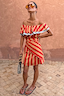 Thumbnail for Tomato Stripe Scarf styled as a red and tan multi-wear off-the-shoulder dress on a model.