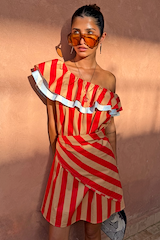Tomato Stripe Scarf in red and tan tied as a wrap over a matching striped mini dress.