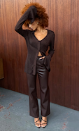 model is wearing brown leather trousers with a brown fitted cardigan 