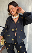 model is wearing the gold snake black shirt and matching trousers with a gold clutch and a chunky shell necklace