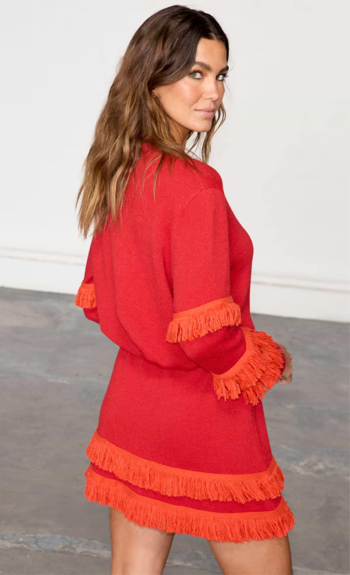 model is wearing the red holly cardigan and matching mini skirt with orange fringing 