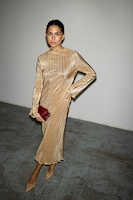 model is wearing gold plisse sophie dress with heels and a burgundy bag.