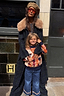 NFD Kids Aspen Jumper with an orange and navy geometric triangle pattern, worn by a child with a woman in a check coat.