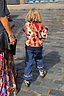 Geometric NFD Kids Aspen Jumper in orange, navy and tan worn by a child walking on a cobblestone street.