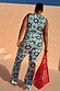 Blue Sun Foldover Trousers in a bright sun and swirl print co-ord, shown from behind on a model with a red mesh bag.