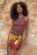 Chocolate Ribbed Tank styled with a colourful fruit print mini skirt against a rustic stone wall.