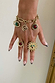 Brushed gold Deloris Charm Bracelet with eye and stone charms, styled on a hand with matching sun and stone rings.