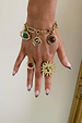 Brushed gold Deloris Charm Bracelet with eye and stone charms, styled on a hand with matching sun and stone rings.