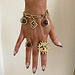 Brushed gold Deloris Charm Bracelet with eye charms, styled with statement sun and stone rings on a hand.