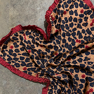 Cherry Leopard Bandana featuring a red ruffled border and cherry-patterned leopard print on a grey stone surface.
