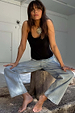 Black Teddy Vest with mesh trim, styled with light wash jeans and a sun necklace on a seated model.