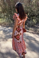 Bridget Print Frida Dress with a multicoloured geometric print and frilled sleeves, shown from the back outdoors.
