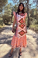 Bridget Print Frida Dress featuring a multicoloured geometric pattern, frilled sleeves and a tiered skirt in the sun.