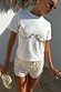 Thumbnail for Cream Shells Hot Pants featuring pearlescent sea shell beads and glass beading, styled for a beach vacation.