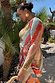 Thumbnail for Sunset Stripe Mesh Midi Dress with a multicoloured stripe print and wrap tie waist in a vacation setting.