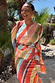 Sunset Stripe Mesh Midi Dress with a multicoloured stripe print and wrap tie waist on a curve model.