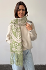 Olive Amara Knit Scarf in a green Mediterranean heart and floral print with tassels, layered over a fuzzy jumper.