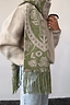 Olive Amara Knit Scarf in green and cream with hand-painted floral motifs and a tasselled hem, worn over a cream jumper.