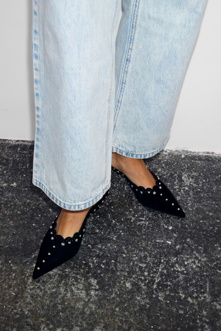 Black Suede Mules featuring scallop edging and silver studs, paired with light-wash blue jeans.