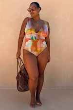 Abstract Plunge Swimsuit in sunset tones with a painterly print, plunging neckline and ruched waist on a curve model.