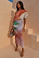Abstract Tilly midaxi dress with metallic gold flecks and a multi-coloured print on a model standing against stone stairs.
