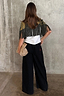 Thumbnail for Olive Amara Knit Cape with tassel fringe and printed motifs, seen from the back with black wide-leg trousers.