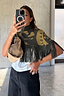 Thumbnail for Olive Amara Knit Cape with a turtle neck, tassel fringe and hand-painted motifs, shown on a model.