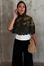 Thumbnail for Olive Amara Knit Cape featuring a turtle neck and long fringe trim with gold floral and heart motifs.