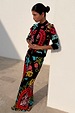 Black Amara Hollie Cardigan with heart and eye motifs, paired with a matching printed skirt against a wall.