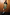 Thumbnail for Olive Amara Knit Mini Dress with hand and flower motifs on a model leaning against a wood-panelled wall.