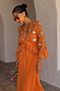 Apricot Embellished Ines Dress in orange with mirror detailing and a peplum hem, styled in a stone archway.