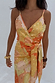 Model wearing the Apricot Strappy Vienna Dress with orange fruit prints, gold foil accents and a wrap waist.