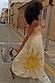 Yellow Stripe Ashley Dress featuring a large sun motif and ruffled bandeau top, captured on a sunlit street.