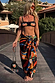 Black Banana Pouch Bag with a beaded banana motif and multicoloured fringe, held by a model on a wooden bridge.