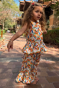 Girl wearing the Girl's Banana Cotton Woven Set with a multicoloured banana print, peplum top and flared trousers.