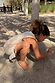 Girl's Banana Jersey Cotton Dress in cream with fringe hem detail, worn by a child playing in the sand.
