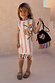 Girl's Banana Jersey Cotton Dress in cream with vertical orange stripes, a colourful banana print and fringe hem.