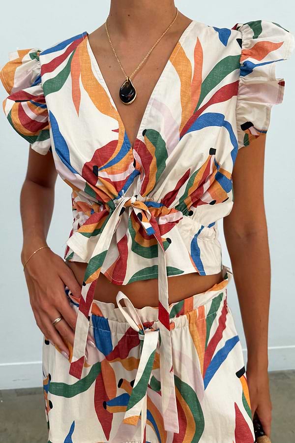 Banana Kerri Top in cream cotton with a colourful banana print, deep V-neckline, puff sleeves, and tie front.