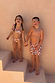 Boy's Banana Print Swim Shorts in cream with a multi-coloured print, worn by a child laughing on stairs.