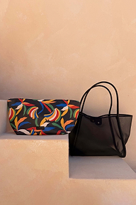 Black mesh tote bag with leather straps and a multi-coloured banana print pouch on neutral steps.