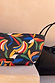 Detachable banana print pouch with a gold-tone logo label, shown with the Black Mesh Tote Bag on a stone surface.